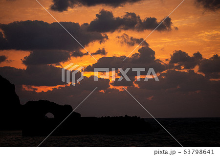 夕焼けに照らし出されるかがんばなトンネルと雲のシルエットの写真素材