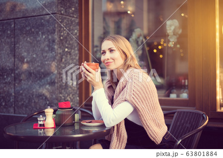 Woman drinks coffee outside of cafe 63801884