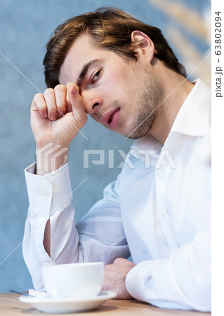 Handsome male looking away sitting at table in cafeteria Handsome male looking away sitting at table in cafeteria 63802094