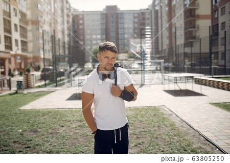 Handsome man standing in a park with a headphones Handsome man standing in a park with a headphones 63805250