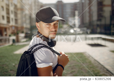 Handsome man standing in a park with a headphones Handsome man standing in a park with a headphones 63805266