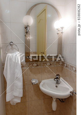 A sink with a mirror lit by a lamp in a small 63808282