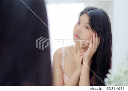 Beautiful young asian woman smiling look at mirror of checking face with skin care and cosmetic 63814031