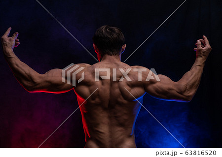Muscular man showing muscles isolated on the black background
