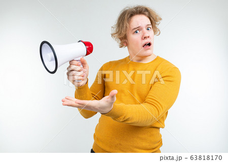 blond wavy guy shouting news into a loudspeaker on a white studio background blond wavy guy shouting news into a loudspeaker on a white studio background 63818170