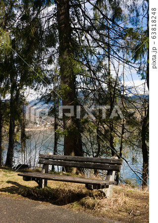Empty wooden bench on shore of beuatiful lake in austrian Alps. Winter sunny morning on lake Hallstatt. The most beautiful lake to explore in Austria. 63818248