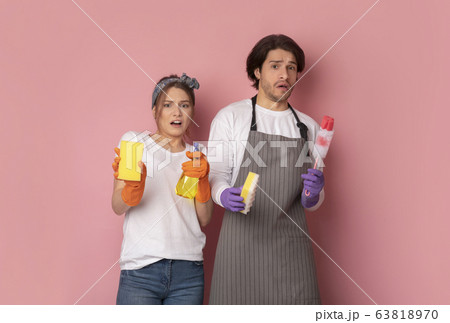 Couple With Cleaning Supplies In Hands Looking With Disgust At Camera Couple With Cleaning Supplies In Hands Looking With Disgust At Camera 63818970