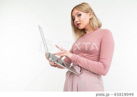attractive blonde girl is typing on a laptop keyboard on a white studio background 63819049