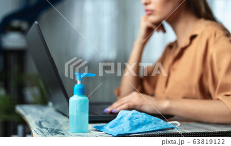 Unrecognizable woman working on laptop with sanitizer gel 63819122