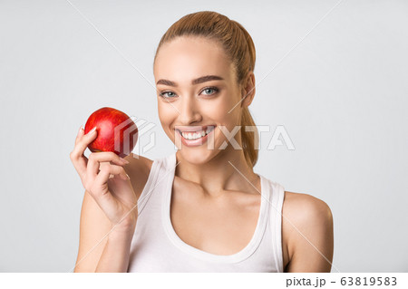 Girl With White Teeth Holding Red Apple Smiling, Gray Background Girl With White Teeth Holding Red Apple Smiling, Gray Background 63819583