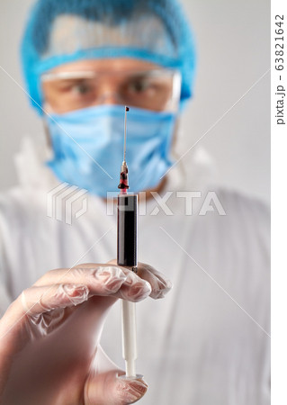 Close up hand holding syringe with dark red blood. 63821642