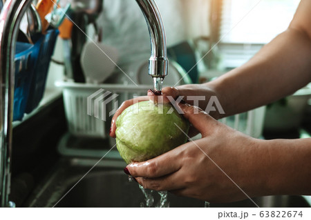 Woman hand is holding a guava and washing with Woman hand is holding a guava and washing with 63822674