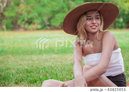Beautiful woman sitting on the grass Beautiful woman sitting on the grass 63825053