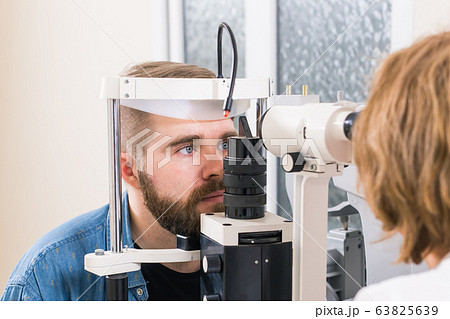 Medicine, health, ophthalmology concept - patient checks her vision by an ophthalmologist. Medicine, health, ophthalmology concept - patient checks her vision by an ophthalmologist. 63825639