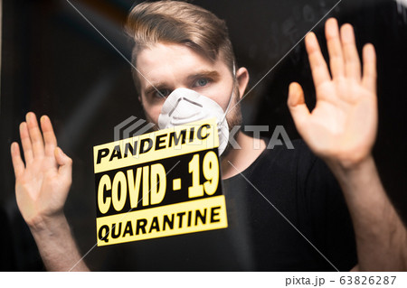 Coronavirus, quarantine, covid-19 and pandemic concept. Sad and sick man of corona virus looking through the window. Stay at home. 63826287