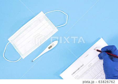 A doctor is conducting a coronovirus test. Doctor's hands with mask and thermometer on a blue background 63826762