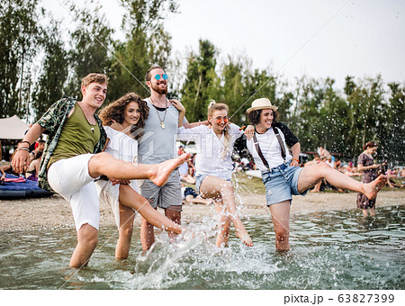 Group of young friends at summer festival, standing in lake. 63827399