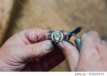 Closeup on hands of goldsmith working on a ring in his workshop Closeup on hands of goldsmith working on a ring in his workshop 63828352