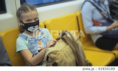 Little girl travel caucasian ride at overground train airtrain with wearing protective medical red mask. Child baby at airtrain. People in mask. Little girl travel caucasian ride at overground train airtrain with wearing protective medical red mask. Child baby at airtrain. People in mask. 63830189