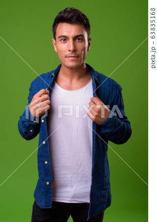 Young handsome Hispanic man against green background 63835168