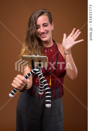 Young beautiful Hispanic woman against brown background Young beautiful Hispanic woman against brown background 63835773
