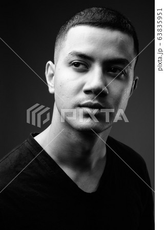 Young multi-ethnic Asian man against black background in black a 63835951