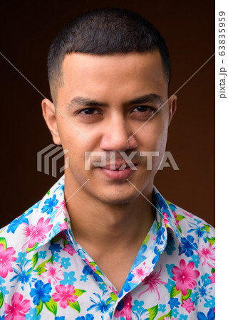 Young multi-ethnic Asian tourist man against brown background 63835959