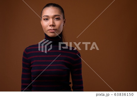 Young beautiful Asian transgender woman against brown background 63836150