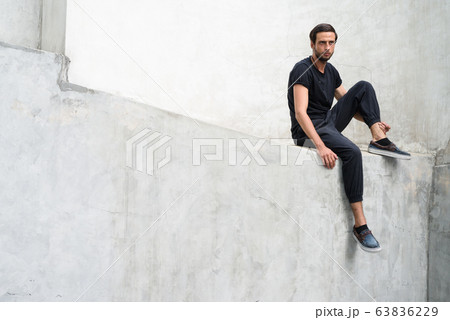 Handsome man against concrete wall in the streets outdoors Handsome man against concrete wall in the streets outdoors 63836229
