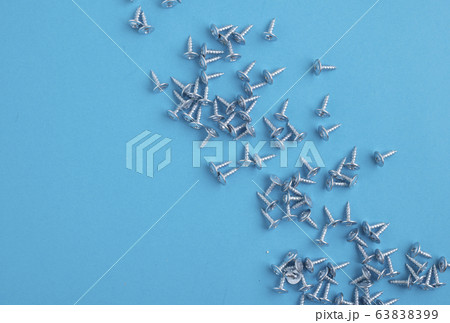 Many screws on blue paper, blurred background 63838399