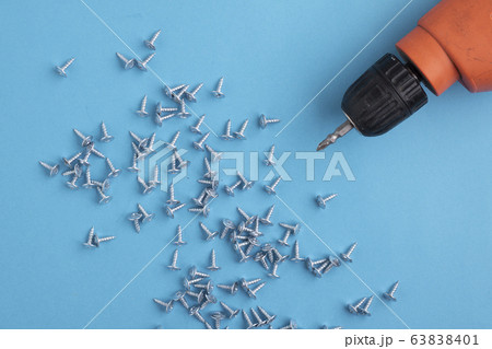 power drill and screws on blue paper. Top view 63838401