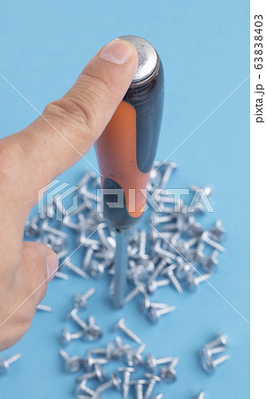 man holding screwdriver, many screws background. man holding screwdriver, many screws background. 63838403