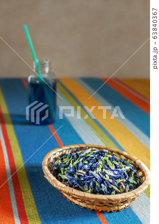 dried blue tea flowers in a wicker basket on a striped tablecloth, tea to go, selective focus 63840367