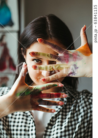 Young talented woman showing hands dirty in paint Young talented woman showing hands dirty in paint 63841135