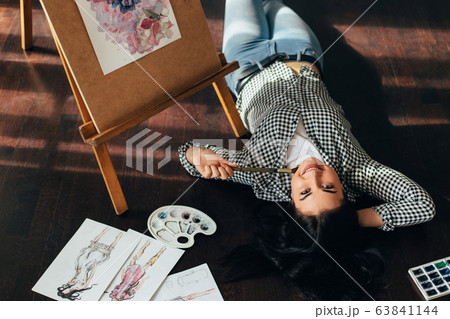 woman dreaming laying on the floor with sketches 63841144