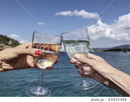 toasting wine glasses against sea and sky in 63842488