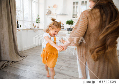 Two sisters play in a bright, stylish kitchen. Beautiful interior. 63842609