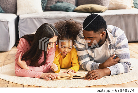 Little african american daughter reading for parents Little african american daughter reading for parents 63848574