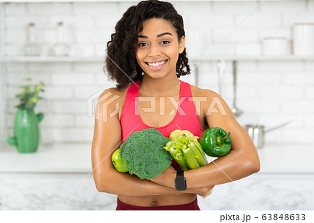 Happy young african girl holding green vegetables Happy young african girl holding green vegetables 63848633
