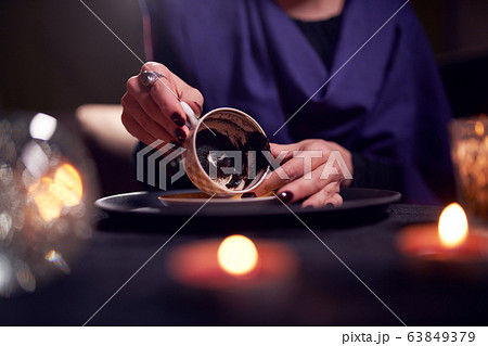 Close-up of fortuneteller's hands divining on coffee grounds at table with predictive ball 63849379