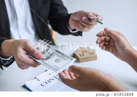 Estate agent giving house keys to client after Estate agent giving house keys to client after 63853898