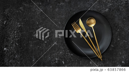 A black plate with golden cuttlery captured from A black plate with golden cuttlery captured from 63857866