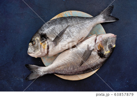 Top view of two dorado fishes on round woden tray Top view of two dorado fishes on round woden tray 63857879