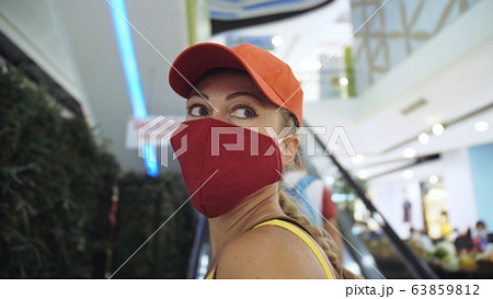 Woman travel caucasian visitor at a supermarket with wearing protective medical mask. Girl tourist customer a grocery store with protect respirator. 63859812
