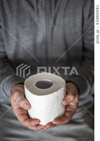 A man holds in his hands a roll of toilet paper. Selective focus. Panic and shortage in stores in A man holds in his hands a roll of toilet paper. Selective focus. Panic and shortage in stores in 63860081