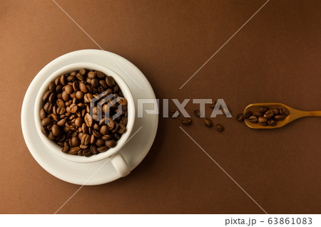 Coffee cup with roasted beans on brown table 63861083