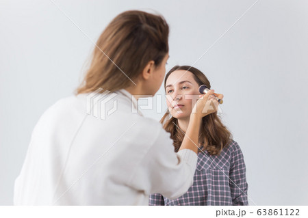 Beauty and cosmetics concept - Makeup artist doing professional make up of young woman Beauty and cosmetics concept - Makeup artist doing professional make up of young woman 63861122