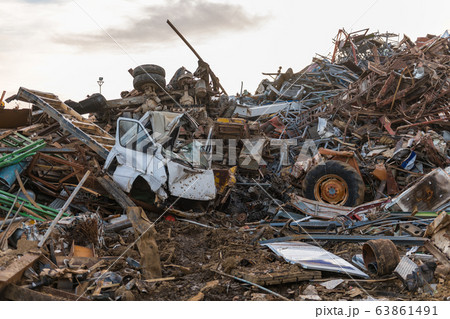 The remains of a truck cabin, wheels and mountains of metal pieces in a junkyard 63861491