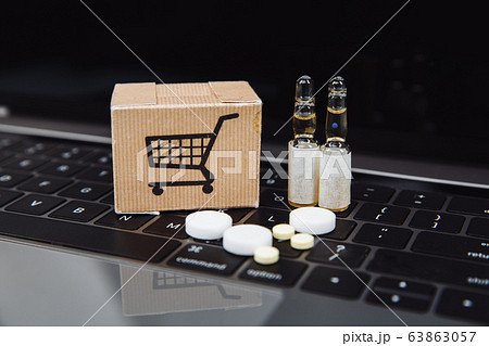 Mini shopping cart full of homeopathic remedies on laptop background. Homeopathy and internet online shopping. 63863057