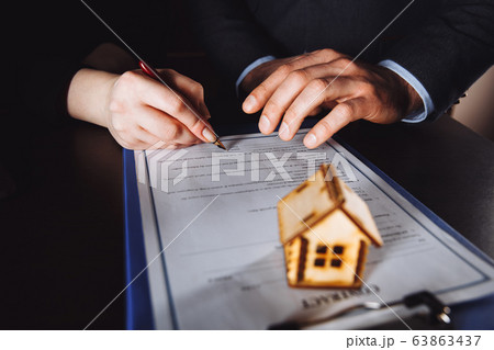 Key of home on hand of bank employeer to sell house after approve loan and buyer signing in contract paper in office. Key of home on hand of bank employeer to sell house after approve loan and buyer signing in contract paper in office. 63863437